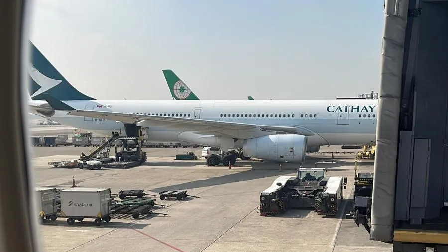 A Cathay Pacific aircraft parked at an airport gate, seen through a cabin window